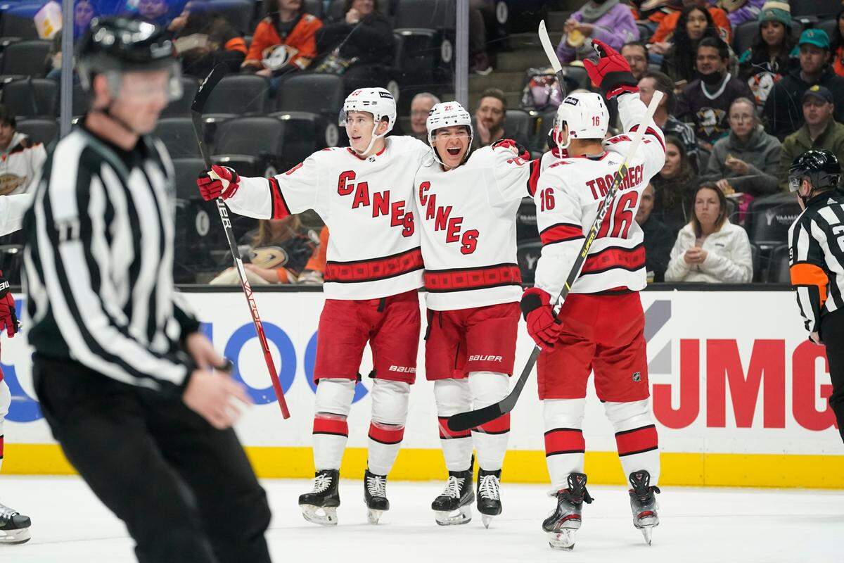 Carolina Hurricanes center Martin Necas (88), defenseman Ethan Bear (25) and center Vincent Trocheck (16) celebrate after Bear scored a goal during the first period of an NHL hockey game against the Anaheim Ducks in Anaheim, Calif., Thursday, Nov. 18, 2021. (AP Photo/Ashley Landis)