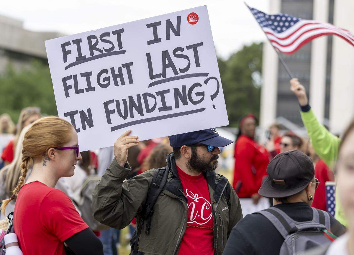 Aaron Schmidt of Raleigh, N.C., shows his support for his wife, and fellow educators, during the May Day protest on the Halifax Mall, on Friday, May 1, 2026 in Raleigh, NC.