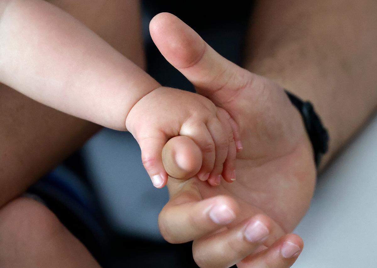 Dr. Alan Rosenbaum’s son holds his hand at their home in Cary.