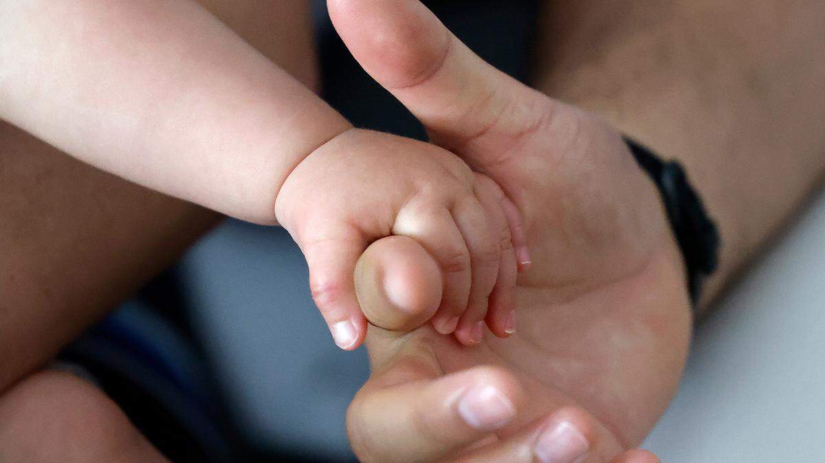 Dr. Alan Rosenbaum, an obstetrician-gynecologist at UNC Rex Hospital, holds his son Eli’s hand during an interview at their home in Cary, N.C. Rosenbaum’s wife, Stefanie Wisda, nearly died during childbirth in 2022.