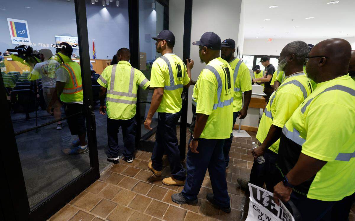 Sanitation workers head into the Durham city council chambers to attend a council work session at City Hall in Durham, N.C., Thursday, Sept. 7, 2023.