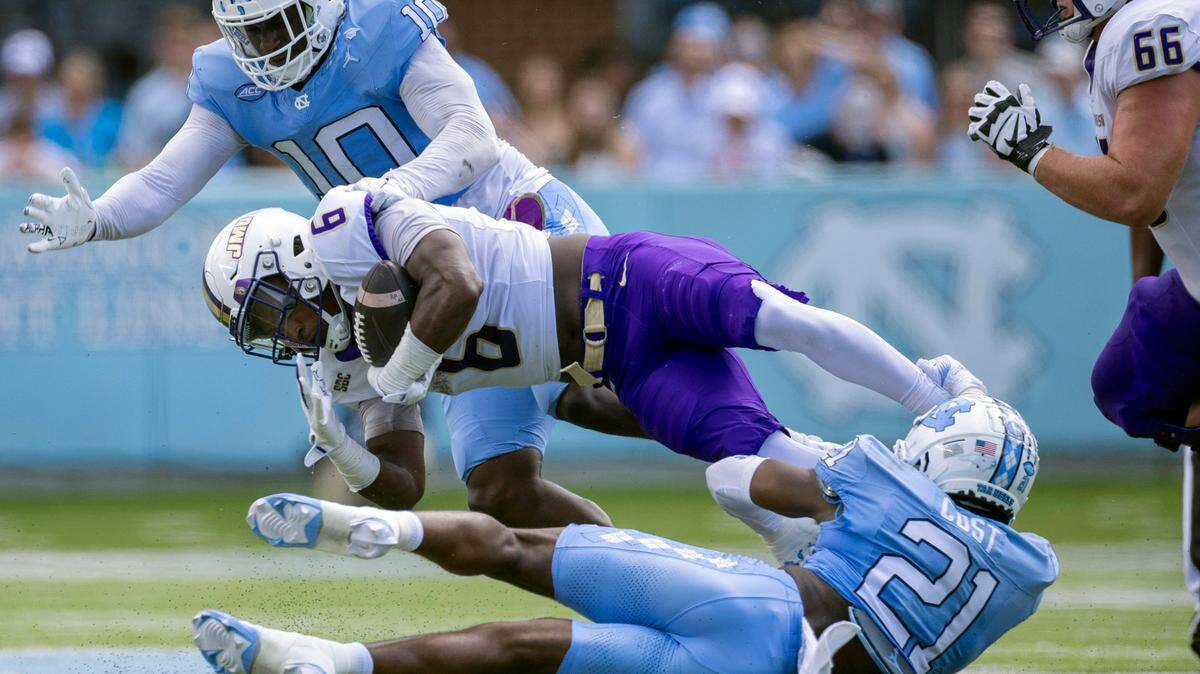North Carolina defensive lineman Desmond Evans (10) and (21) defensive back Kaleb Cost (21) work to stop James Madison running back George Pettaway (6) after a two yard gain in the first quarter on Saturday, September 21, 2024 at Kenan Stadium in Chapel Hill, N.C. Pettaway, a former Tar Heel rushed for 65 yards in the first half.