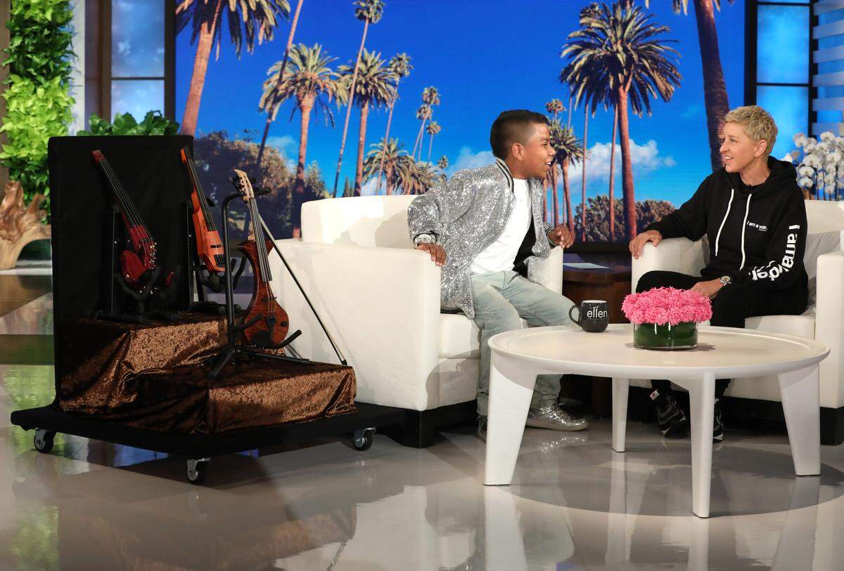 Ellen DeGeneres, right, presents Raleigh violinist Tyler Butler-Figueroa, left, with three violins during a taping of “The Ellen DeGeneres Show” in Burbank, Calif.