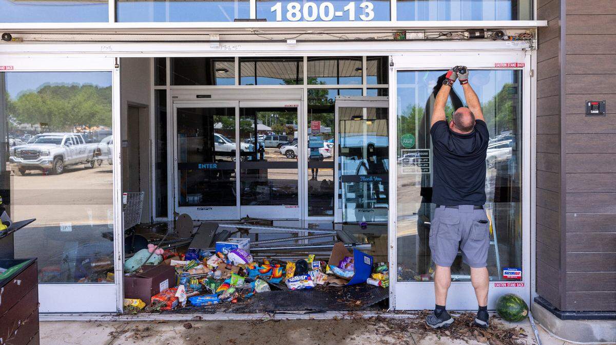 Workers secure the entrance of an Aldi grocery store in Eastgate Crossing in Chapel Hill on Monday, July 7, 2025, after floodwaters surged about 5 feet inside businesses at the shopping center. The flooding was caused by heavy rain from Tropical Storm Chantal, which triggered flash flooding in parts of Orange, Durham, and Chatham counties.