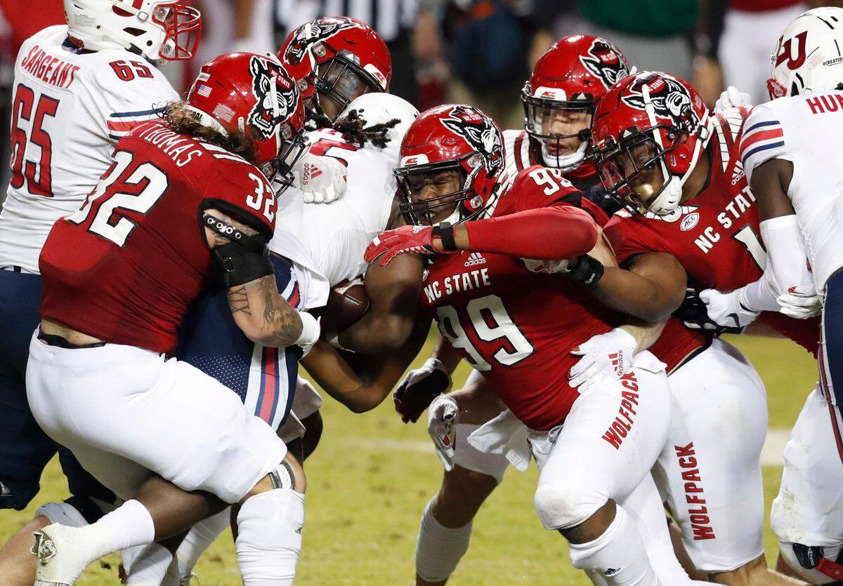 From left, N.C. State’s Drake Thomas (32), Alim McNeill (29), Daniel Joseph (99), Isaac Duffy (33) and Isaiah Moore (1) stop Liberty running back Peytton Pickett (25) during the first half of N.C. State’s game against Liberty at Carter-Finley Stadium in Raleigh, N.C., Saturday, Nov. 21, 2020.