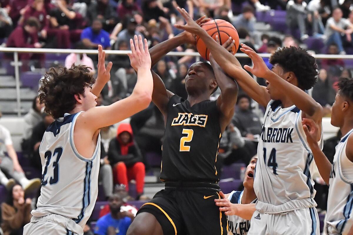 Farmville Central’s Jah Short (2) shoots against Millbrook’s Colt Langdon (23) and Kyrie Heredia (14) during the first half. The Millbrook Wildcats and the Farmville Central Jaguars met in the John Wall Holiday Invitational in Raleigh, N.C. on December 29,2022 .