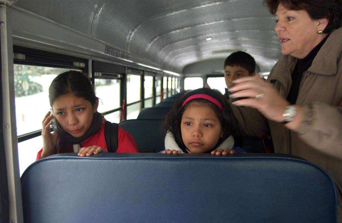 A surprise snow and ice storm paralyzed the Raleigh area in January 2005. Green Elementary's Monica Bernal Mendoza, 8, left, assures her parents that she is safe as she calls from the school bus that was stuck on Quail Hollow Drive in North Raleigh. Lynda Davis, right, who lives on Quail Hollow Drive, came onboard to offer help to the stranded bus.