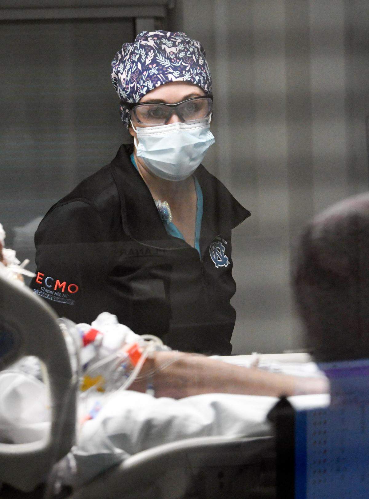 Dr. Lauren Raff checks on a COVID patient on an ECMO machine in the Surgical Trauma ICU at UNC Hospital in Chapel Hill, N.C., Thursday, January 27, 2022. ECMO stands for extracorporeal membrane oxygenation and the machine pumps and oxygenates a patient’s blood outside the body, allowing the heart and lungs to rest.