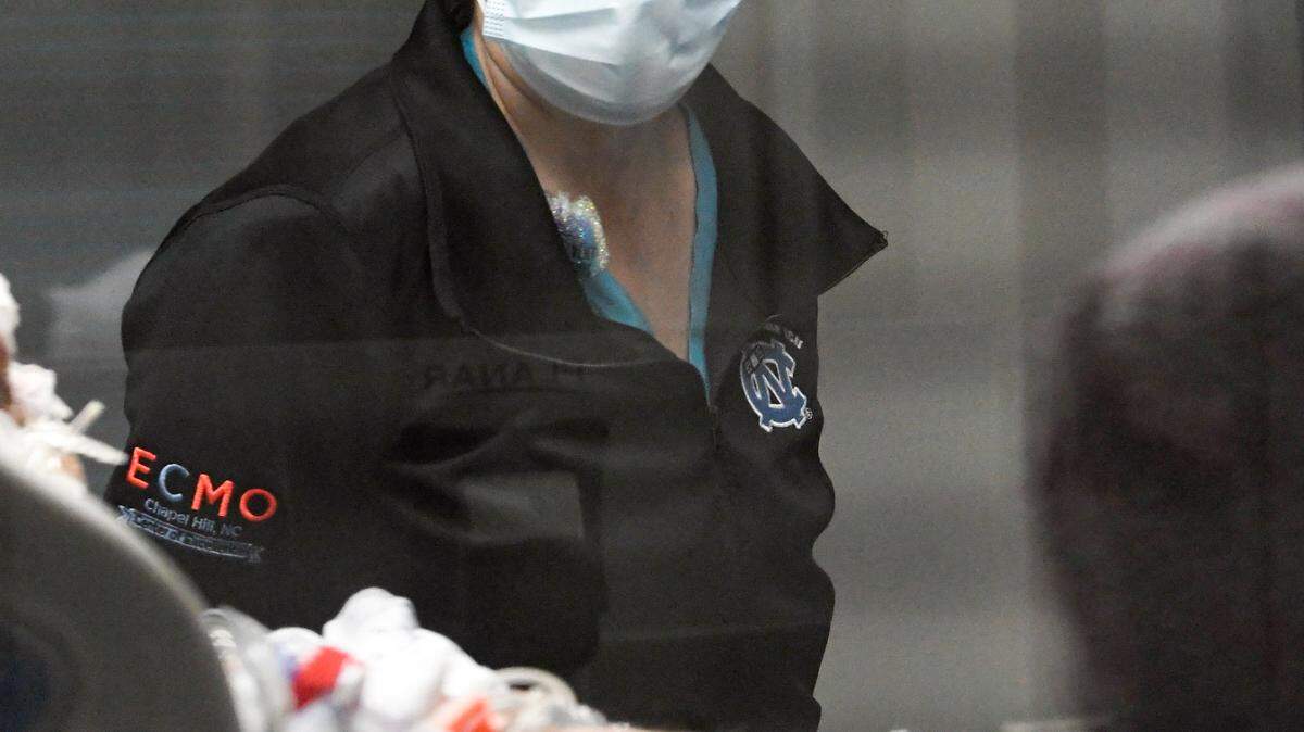 Dr. Lauren Raff checks on a COVID patient on an ECMO machine in the Surgical Trauma ICU at UNC Hospital in Chapel Hill, N.C., Thursday, January 27, 2022. ECMO stands for extracorporeal membrane oxygenation and the machine pumps and oxygenates a patient’s blood outside the body, allowing the heart and lungs to rest.