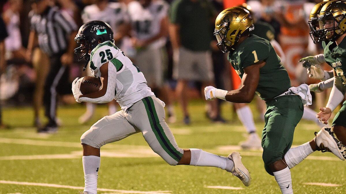 Leesville Road’s Jay Snelling (25) runs for the first down ahead of Cardinal Gibbons’ Will Mason (1) during the first quarter. The Cardinal Gibbons Crusaders and the Leesville Road Pride met in a football game in Raleigh , N.C. on October 8, 2021.