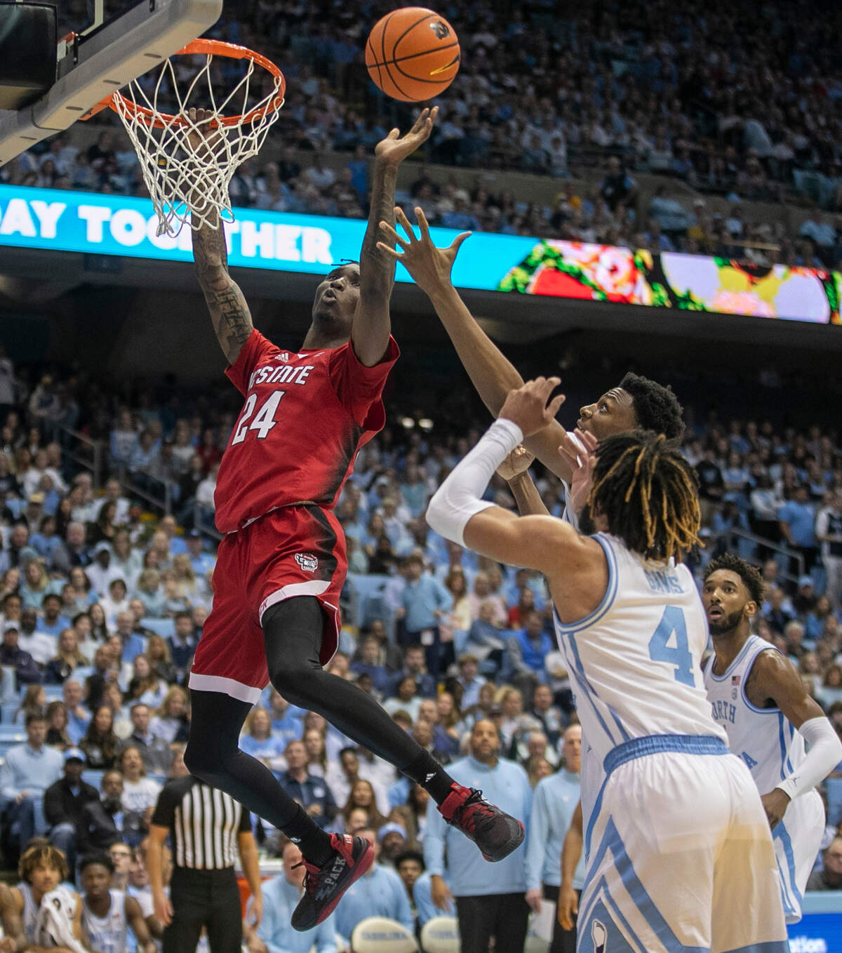 N.C. State’s Ernest Ross (24) hangs on the rim and works to control his own rebound during the first half against North Carolina on Saturday, January 21, 2023 at the Smith Center in Chapel Hill, N.C.