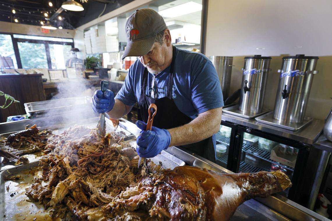 Picnic owner Chris Holloway pulls the meat from a smoked pig before lunch service at Picnic in Durham, N.C., Saturday, August 23, 2025. The restaurant specializes in whole hog barbecue.