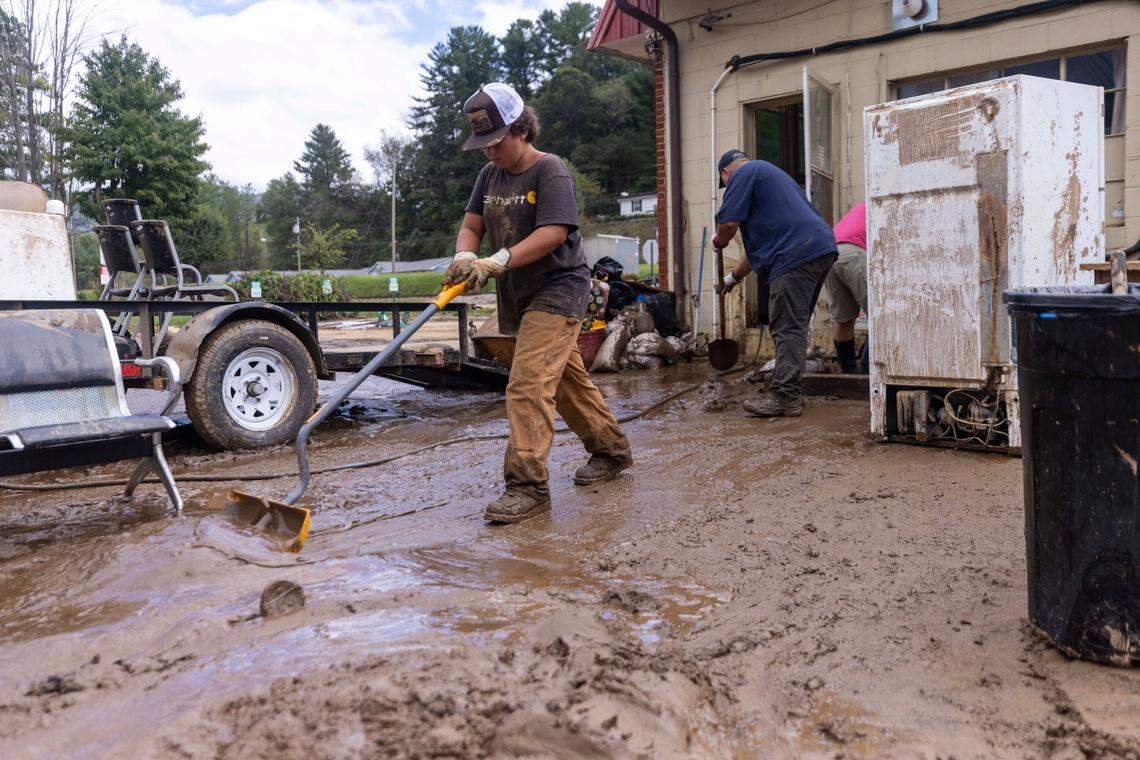Blake Nelson, 11, and his father Mitch Nelson clean up a flooded salon in Clyde on Saturday, Sept. 28, 2024 after massive flooding damaged dozens of homes and businesses. The remnants of Hurricane Helene caused widespread flooding, downed trees, and power outages in western North Carolina.