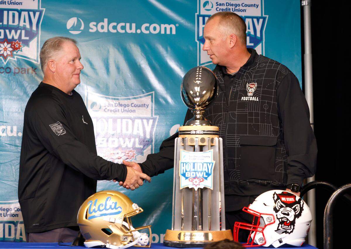 N.C. State head coach Dave Doeren and UCLA head coach Chip Kelly shake hands after a press conference at Petco Park in San Diego, CA Monday, Dec. 27, 2021, a day before the Holiday Bowl.