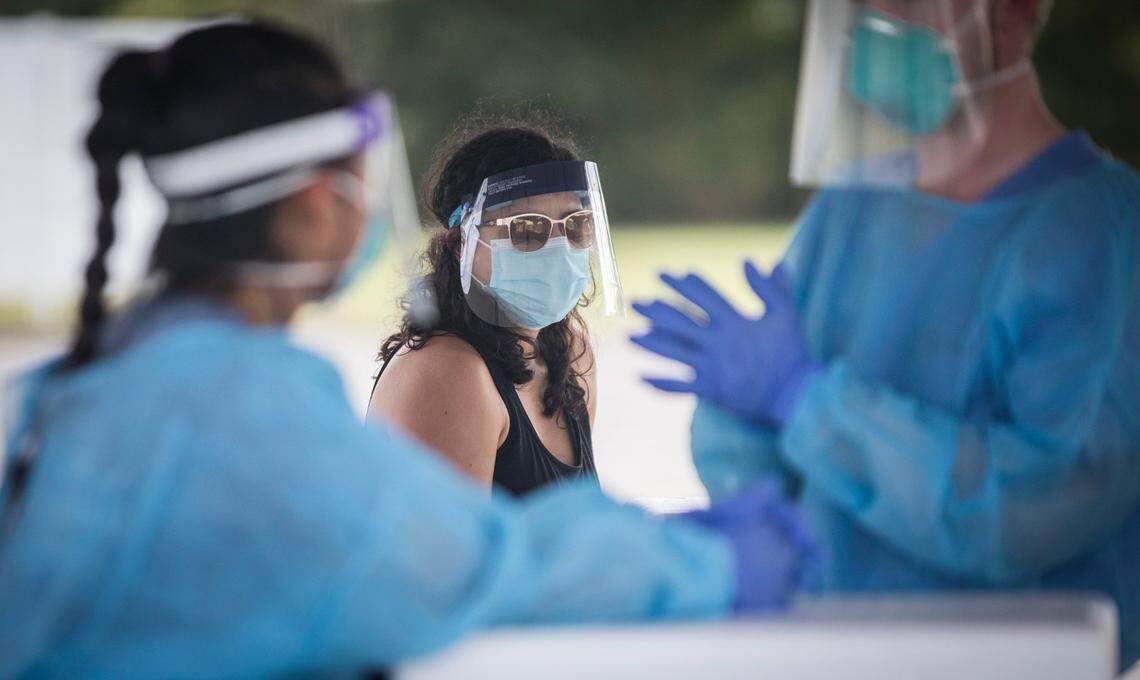 UNC Health project manager Karen Roque, middle, waits with Piedmont Health employees Mookho Paw, left, and Matthew Hutchens, right, for people to arrive for their COVID-10 tests at a drive-thru at the Dennis A. Wicker Center in Sanford, N.C. on Tuesday, Aug. 25, 2020.