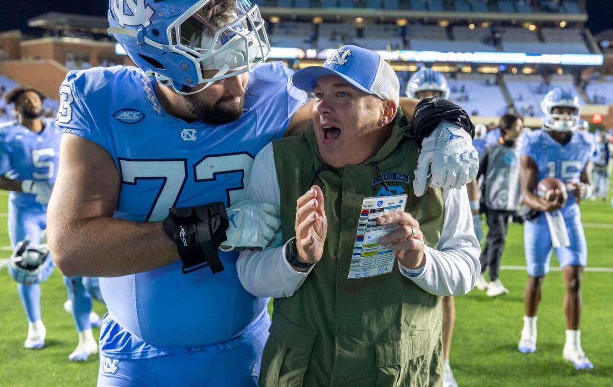 North Carolina offensive lineman Eli Sutton (73) embraces defensive coordinator Geoff Collins as they leave the field following the Tar Heels’ 31-24 victory over Wake Forest on Saturday, November 16, 2024 at Kenan Stadium in Chapel Hill, N.C.