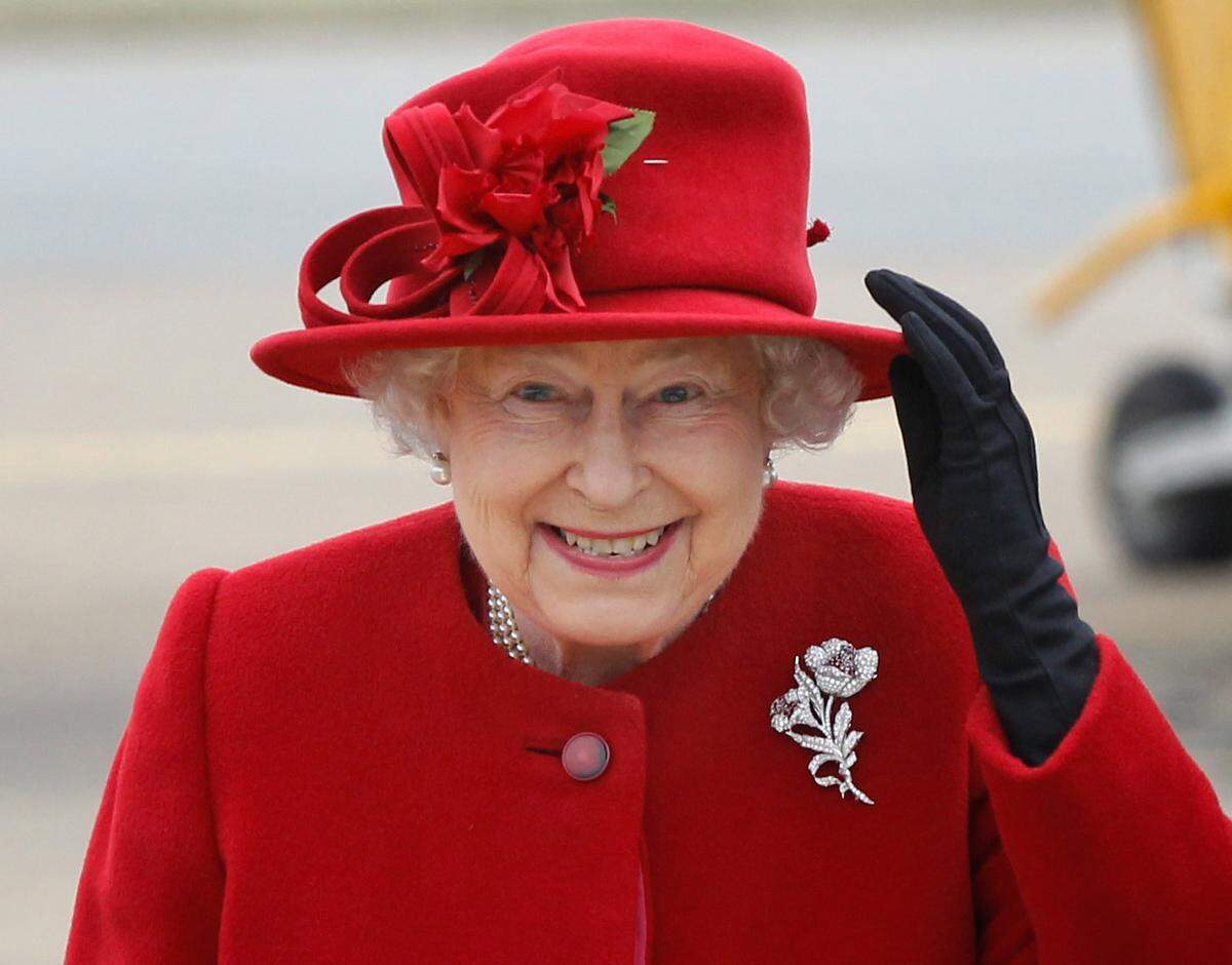 Britain’s Queen Elizabeth II holds on to her hat in high winds as she arrives for a visit to RAF Valley, Anglesey, Wales, where her grandson Prince William, is stationed as a search and rescue helicopter pilot Friday April 1, 2011.