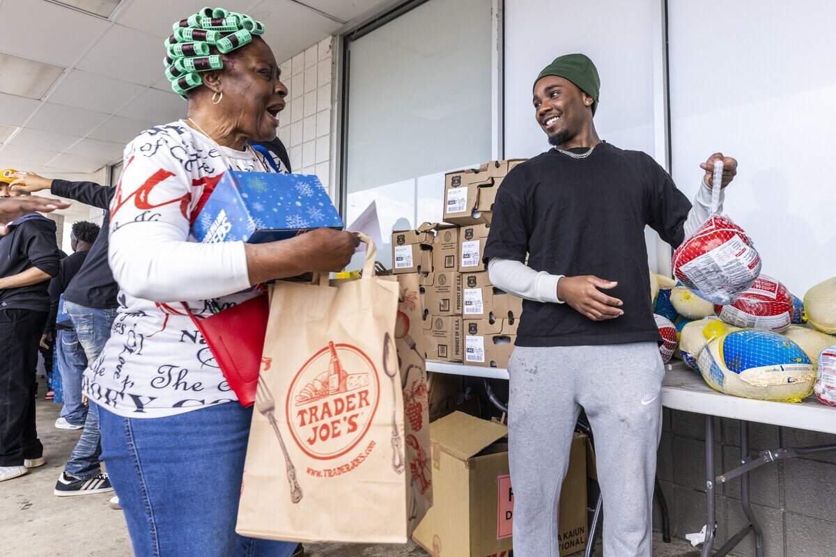 Volunteer Evan Williams, right, gives away free turkeys during the fourth annual Thanksgiving Block Party food giveaway hosted by Hot 97.9 FM radio station outside Food Lion on Raleigh Boulevard in Raleigh on Saturday, Nov. 22, 2025. Station owner “Dy-Nasty” said the event distributed 400 boxes and bags of groceries and 200 frozen turkeys with help from area businesses, churches and civic groups.