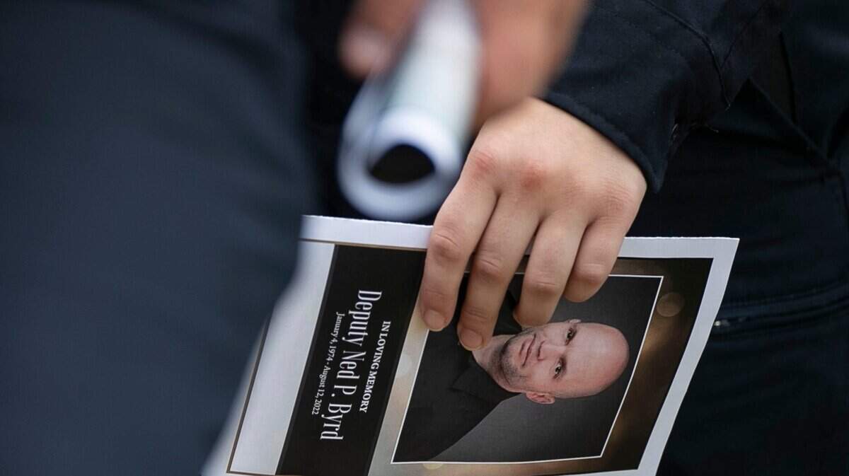 Law enforcement officers carry funeral programs with a photograph of Wake County Deputy Ned Byrd on them as they leave his service at Providence Baptist Church on Friday, August 19, 2022 in Raleigh, N.C.