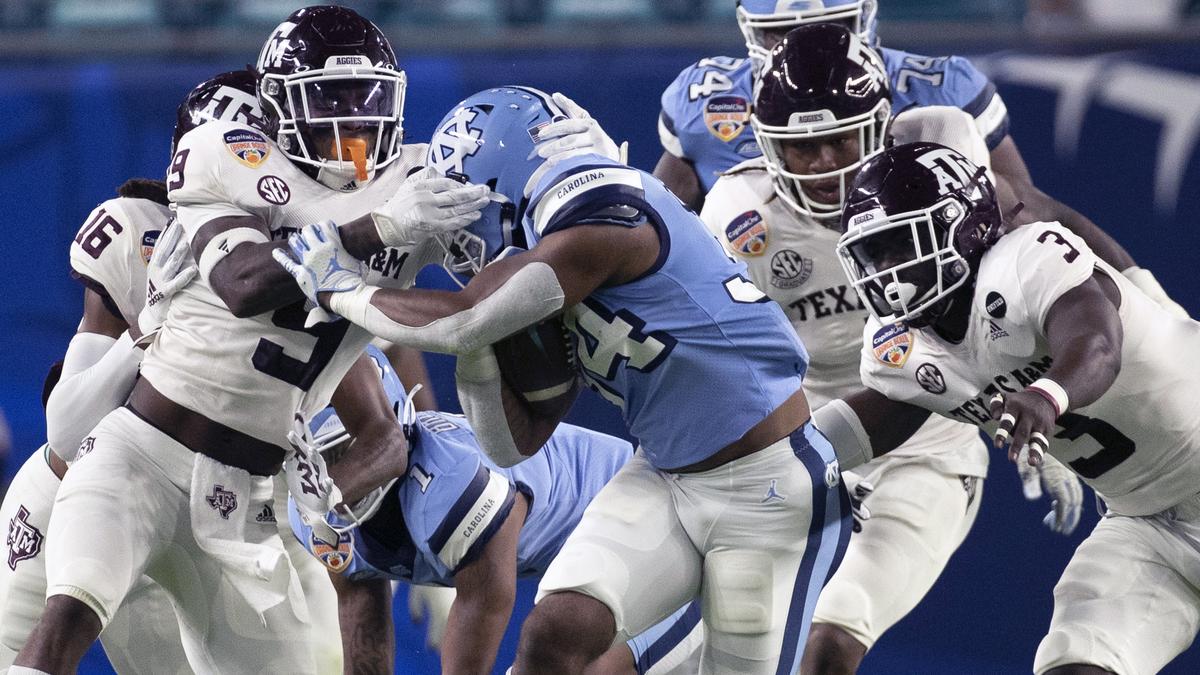 North Carolina’s British Brooks (34) is stopped by Texas A&M’s Leon O’Neal Jr. (9) in the first quarter of the Capital One Orange Bowl on Saturday, January 2, 2021in Miami Gardens, Florida. O’Neal was called for a face mask penalty.