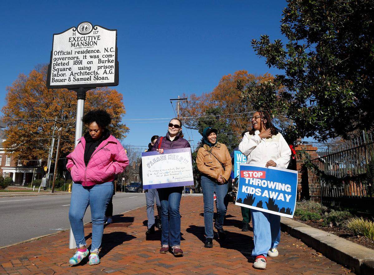 People hold signs while marching around the Executive Mansion as a part of the Vigil for Freedom and Racial Justice on Thursday, Dec. 1, 2022, in Raleigh, N.C. Community advocates will hold vigil daily outside the Executive Mansion throughout the month of December to call for justice and fair treatment of people incarcerated in North Carolina prisons.
