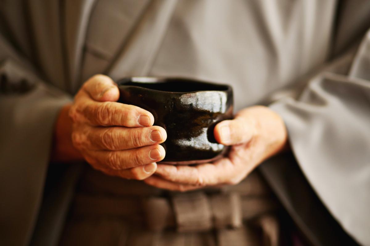 George Yamazawa holds a tea bowl after a tea ceremony lesson at his Durham restaurant, Yamazushi.