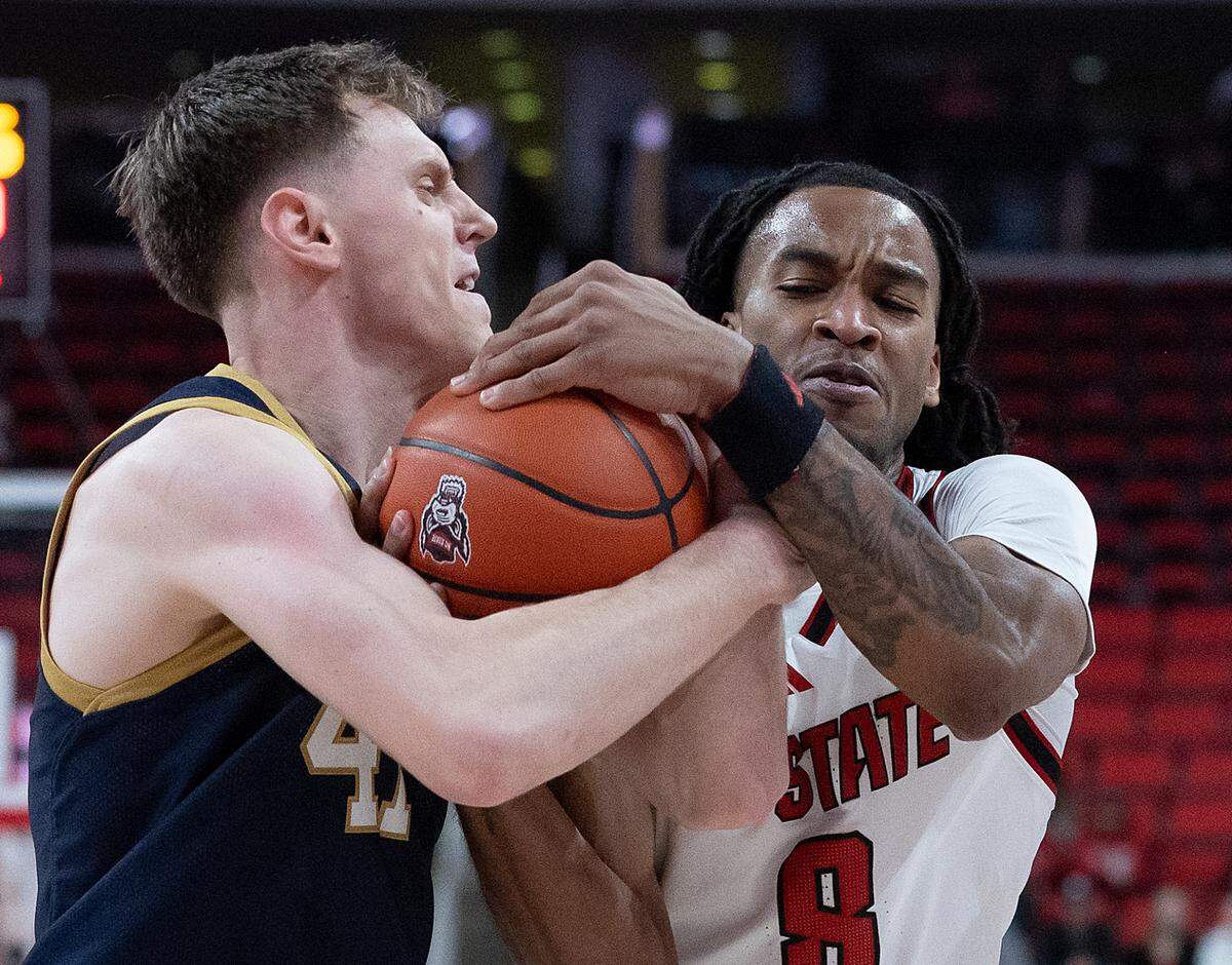 Notre Dame’s Matt Allocco and N.C. State’s Jayden Taylor get tied up during the first half of the Wolfpack’s 66-65 win on Wednesday, Jan. 8, 2025, at Lenovo Center in Raleigh, N.C.