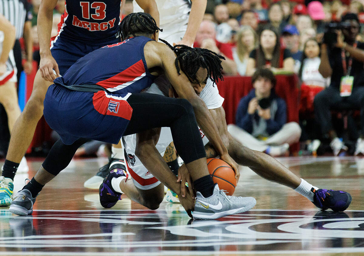 N.C. State’s Jayden Taylor and Detroit’s Marcus Tankersley dive on the floor for a loose ball during the first half of the Wolfpack’s game on Saturday, Dec. 23, 2023, at PNC Arena in Raleigh, N.C.