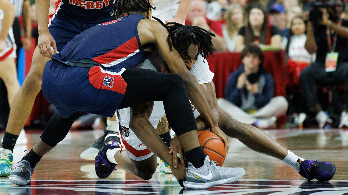 N.C. State’s Jayden Taylor and Detroit’s Marcus Tankersley dive on the floor for a loose ball during the first half of the Wolfpack’s game on Saturday, Dec. 23, 2023, at PNC Arena in Raleigh, N.C.