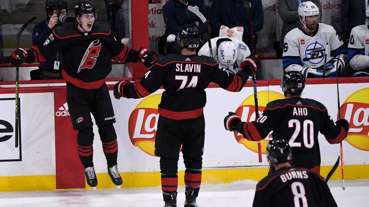 Carolina Hurricanes’ Martin Necas (88) celebrates with Jaccob Slavin (74) and Sabastian Aho (20) after his goal against the Winnipeg Jets during third-period NHL hockey game action in Winnipeg, Manitoba, Monday, Nov. 21, 2022. (Fred Greenslade/The Canadian Press via AP)