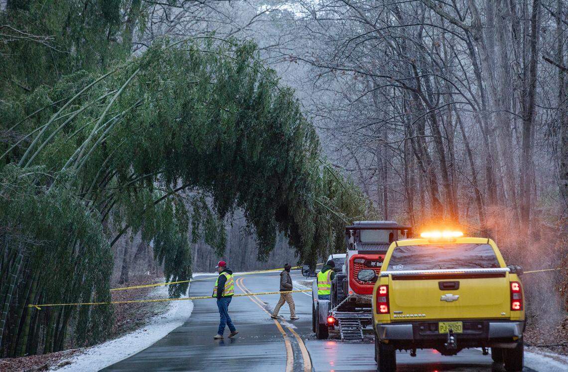 A NC Dept. of Transportation crew prepares to clear a tree drooping from the weight of ice that blocks Yates Mill Pond Road near the intersection with Penny Road south of Downtown Raleigh Saturday morning.