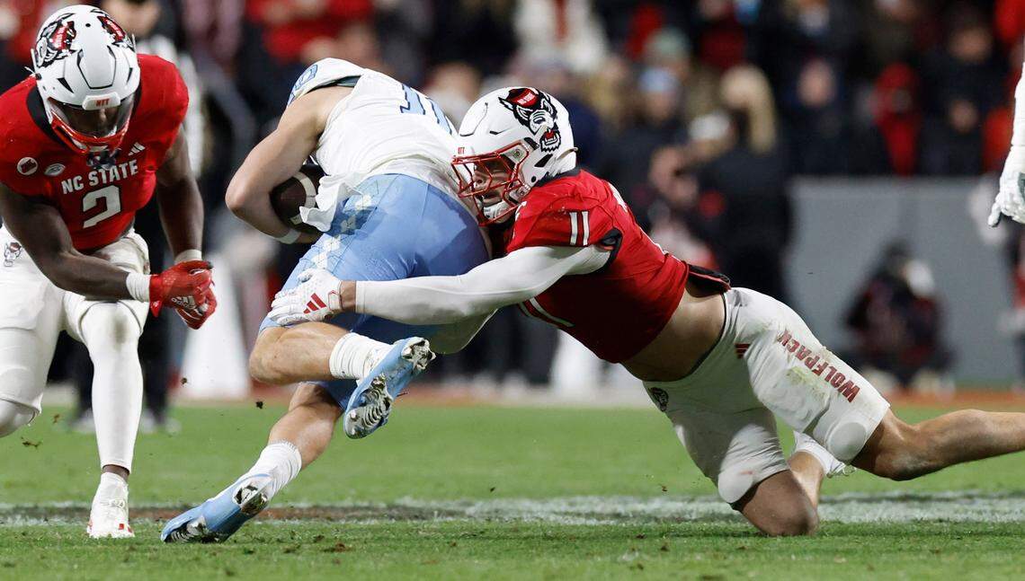 N.C. State linebacker Payton Wilson (11) tackles North Carolina quarterback Drake Maye (10) during the first half of N.C. State’s game against UNC at Carter-Finley Stadium in Raleigh, N.C., Saturday, Nov. 25, 2023.