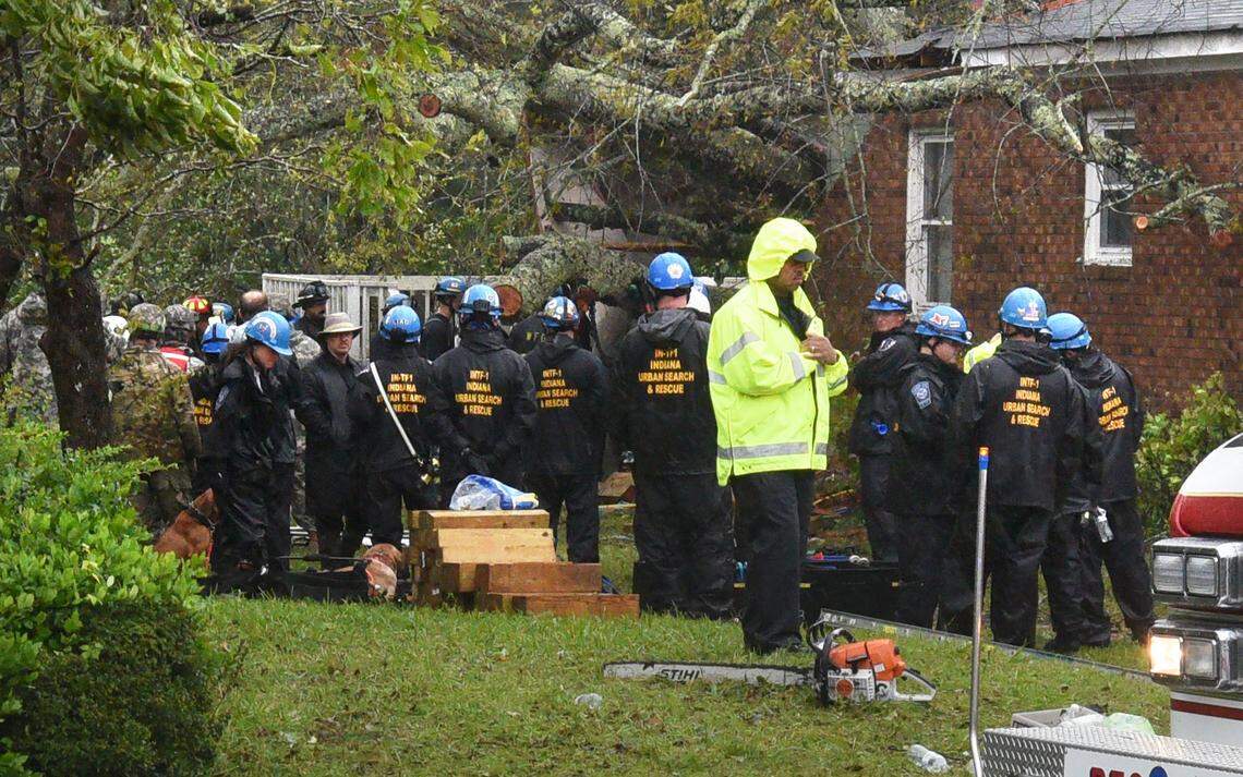 Rescue workers, police and fire department members wait to remove the bodies of a mother and child who were killed by a falling tree as Hurricane Florence made landfall in  Wilmington, N.C., on Friday Sept. 14, 2018. The father was transported to the hospital with serious injuries.