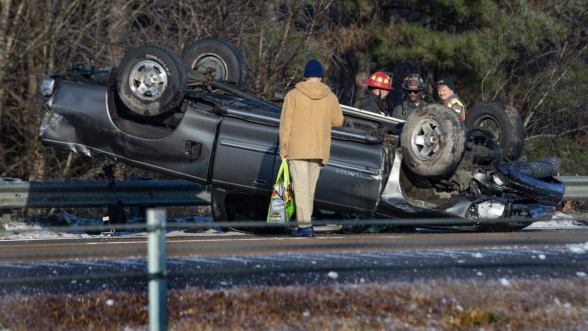 Firefighters and the driver survey the remains of an overturned car in the westbound lanes of US 64 in Wendell Saturday morning as many slick spots remain, even on main roads and bridges.