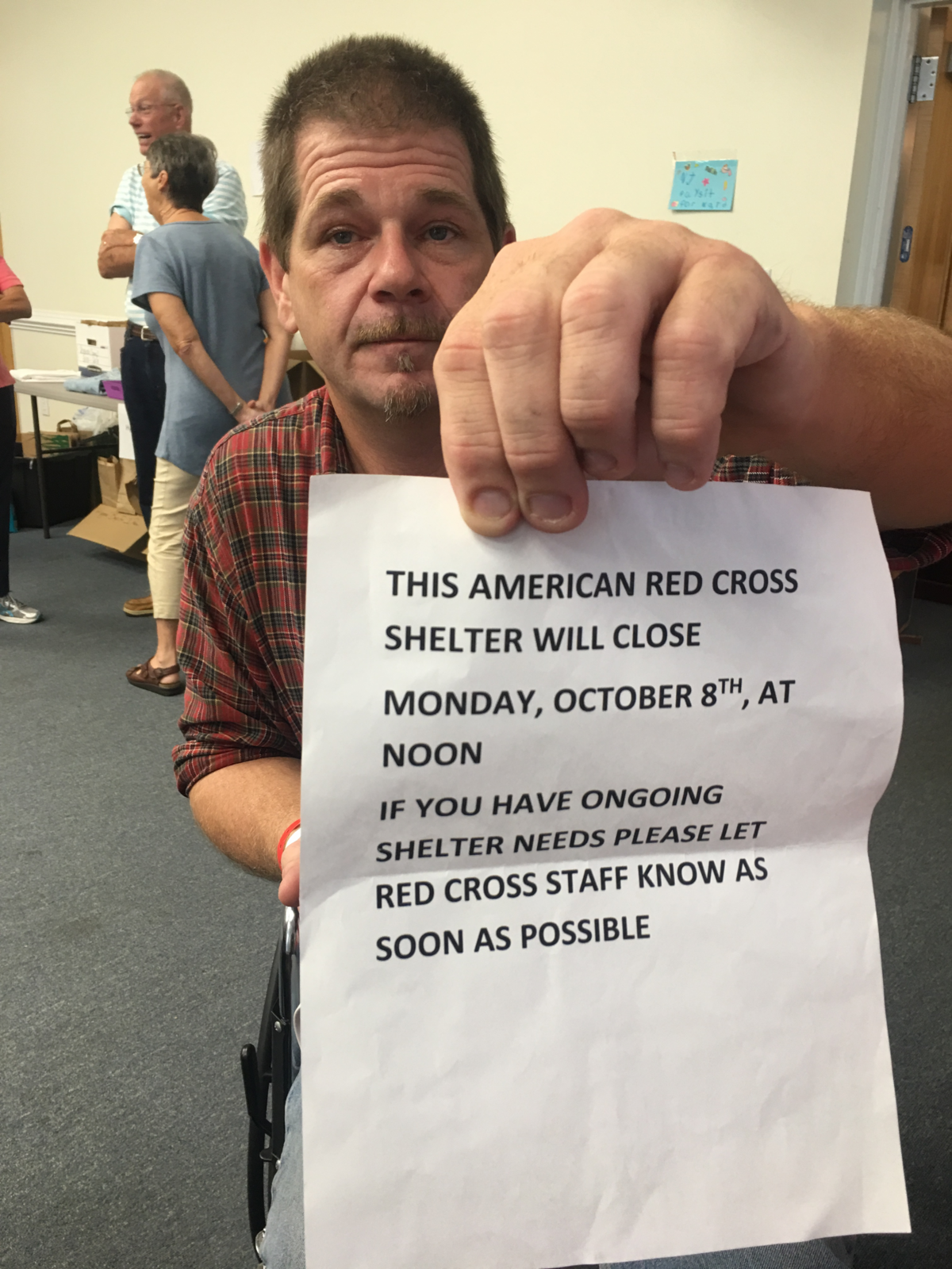 Daniel Brant, 50, holds up a sign Saturday announcing the Red Cross shelter where he is staying will close on Monday. The Red Cross reversed that decision on Sunday.