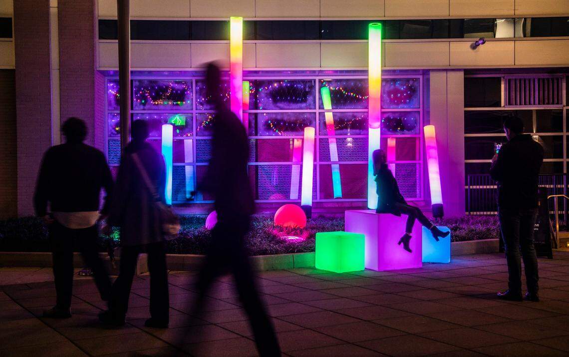 Pedistrians check out the “Glow Zone”in City Plaza in downtown Raleigh Friday, Dec. 2, 2022. The large-scale, interactive light-based art piece is one of 18 installations around downtown Raleigh and the Glenwood South district that make up the Illuminate Art Walk presented by Wake Tech.