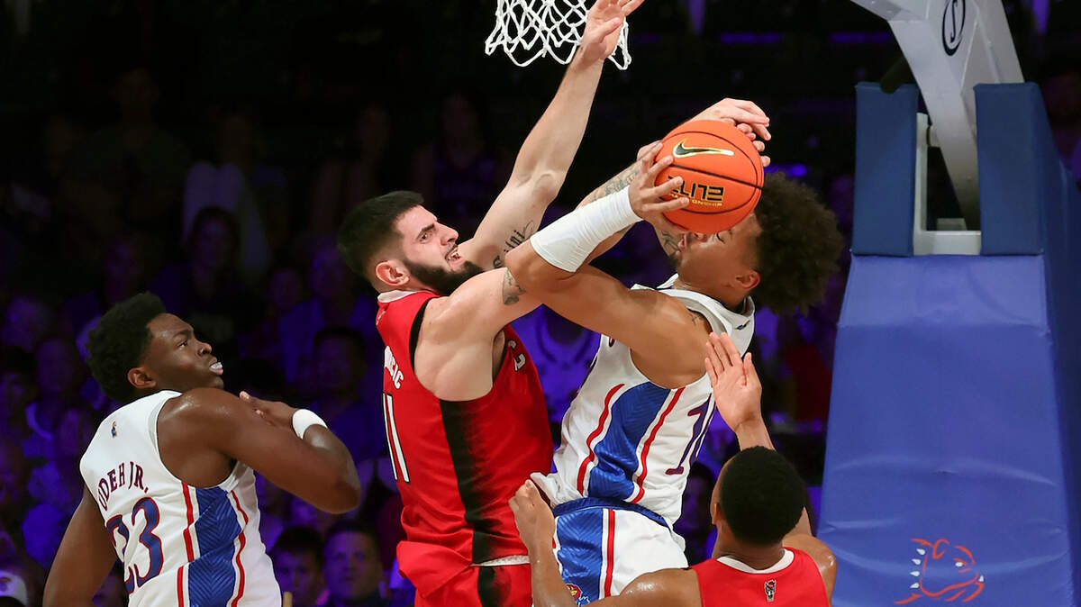 This photo provided by Bahamas Visual Services shows N.C. State’s Dusan Mahorcic, center left, blocking Kansas forward Jalen Wilson, center right, as teammates look on during an NCAA college basketball game between at the Battle 4 Atlantis at Paradise Island, Bahamas, Wednesday, Nov. 23, 2022.(Tim Aylen/Bahamas Visual Services via AP)