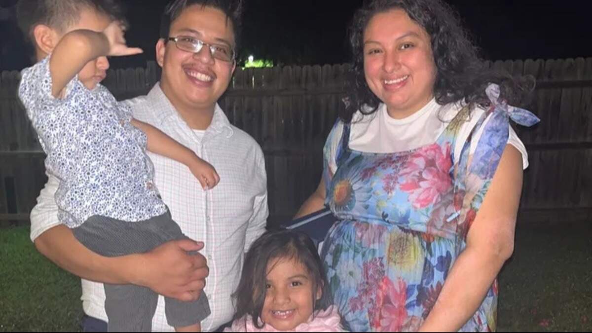 Moises Benitez Diaz is holding his son, Elijah, while wearing a white-checkered button down shirt and glasses with a black frame. He stands next to his wife, Esmeralda Escobar, wearing a white shirt under her blue dress with pink, yellow and blue flowers. In the middle is the couple’s daughter, Rochelle.