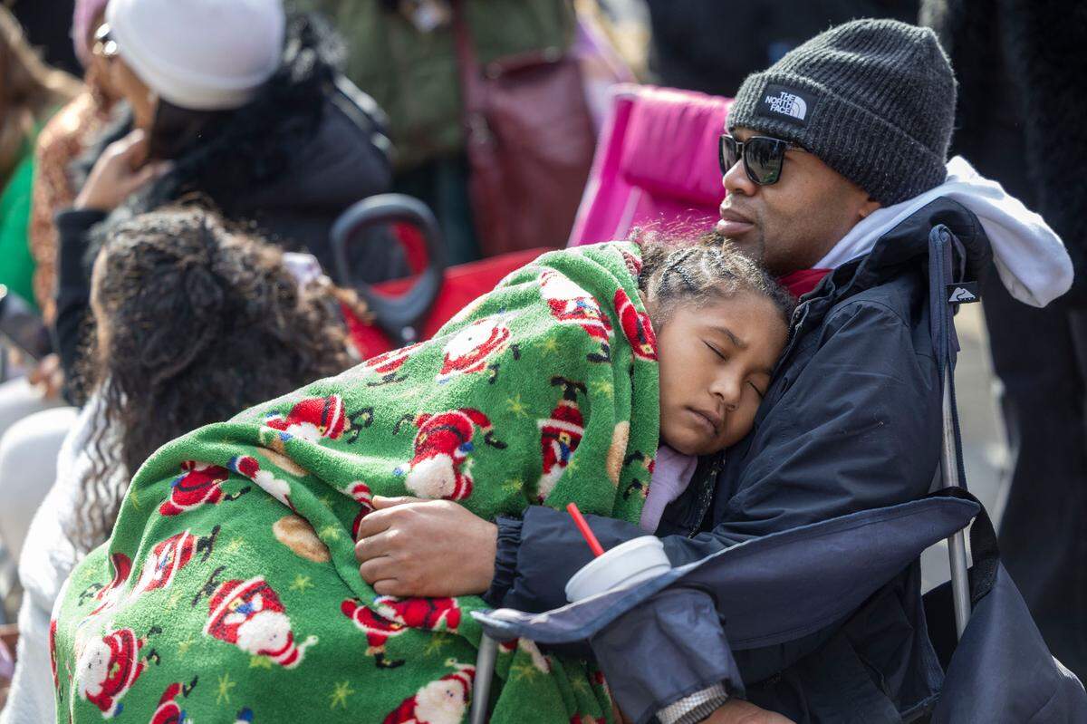 A parade attendee catches a nap after an early start, to stake out a front row spot for the 80th annual Raleigh Christmas Parade on Saturday, November 23, 2024 in Raleigh, N.C.