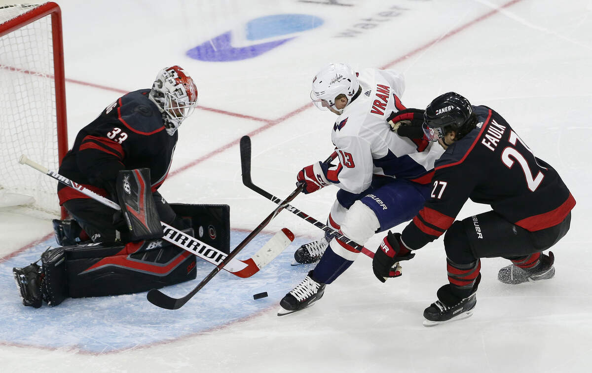 Washington Capitals’ Jakub Vrana (13), of the Czech Republic, is blocked by Carolina Hurricanes goalie Scott Darling (33) while Hurricanes’ Justin Faulk (27) defends during the third period of an NHL hockey game in Raleigh, N.C., Friday, Dec. 14, 2018. Washington won 6-5 in a shootout. (AP Photo/Gerry Broome)