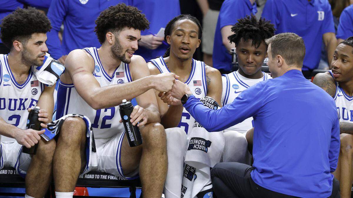 Duke’s Jon Scheyer fist-bumps Cameron Boozer (12) late in the game while congratulating Cayden Boozer (2), Maliq Brown (6), Patrick Ngongba (21) and Maliq Brown (6) late in the second half of Duke’s 81-58 victory over TCU in the second round of the NCAA Men’s Basketball Tournament at  Bon Secours Wellness Arena in Greenville, S.C., Saturday, March 21, 2026.