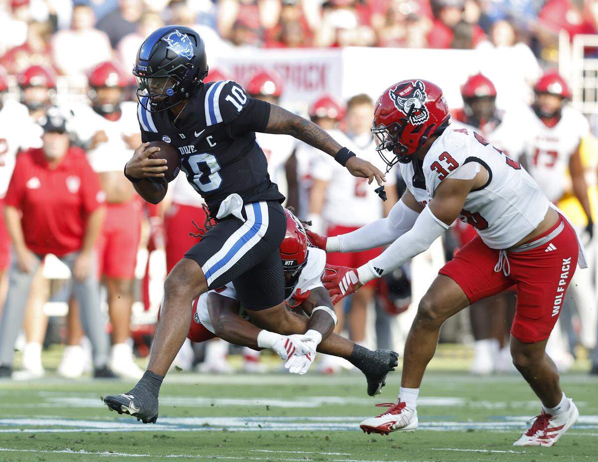 Duke quarterback Darian Mensah runs the ball under pressure from N.C. State’s Jamel Johnson and Kenny Soares Jr. during the first half of the Blue Devils’ 45-33 win on Saturday, Sept. 20, 2025, at Wallace Wade Stadium in Durham, N.C.