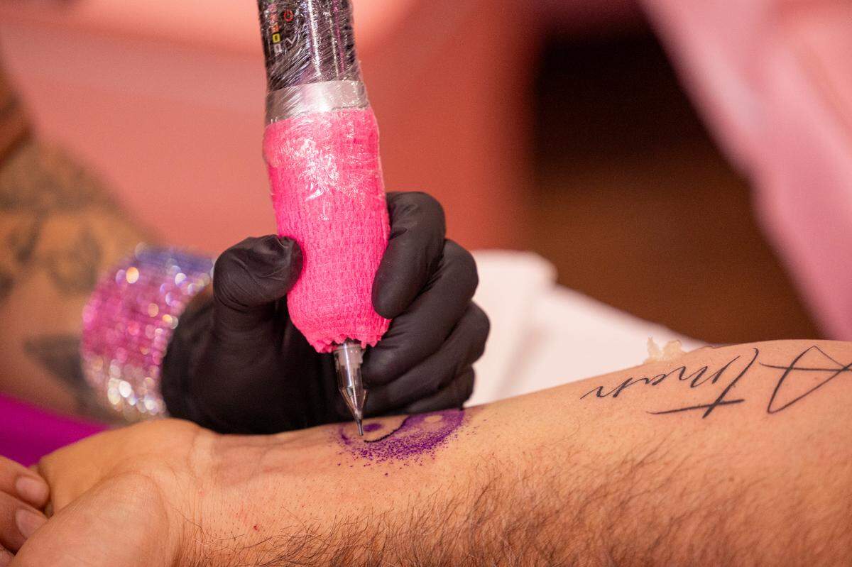 Camila Gama Marrache applies a tattoo to Dante Zambrano during the grand opening of her new studio, Beauty Art Studio, on Franklin Street in Chapel Hill on Saturday, Sept. 7, 2024. Marrache lost her right arm to a botched liposuction procedure last year.