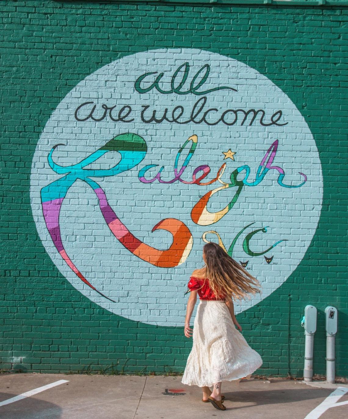 Samantha Oppenheimer at Luke Miller Buchanan’s “All Are Welcome” mural in downtown Raleigh, NC. The mural is a popular spot for Raleigh’s Instagrammers.