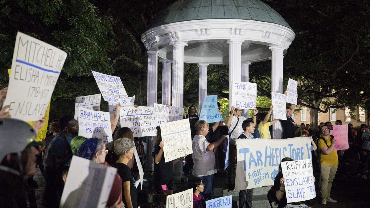 At a 2019 protest, students, community members and activists hold signs with the names of slave owning people who have buildings named after them on the University of North Carolina campus in Chapel Hill, N.C.