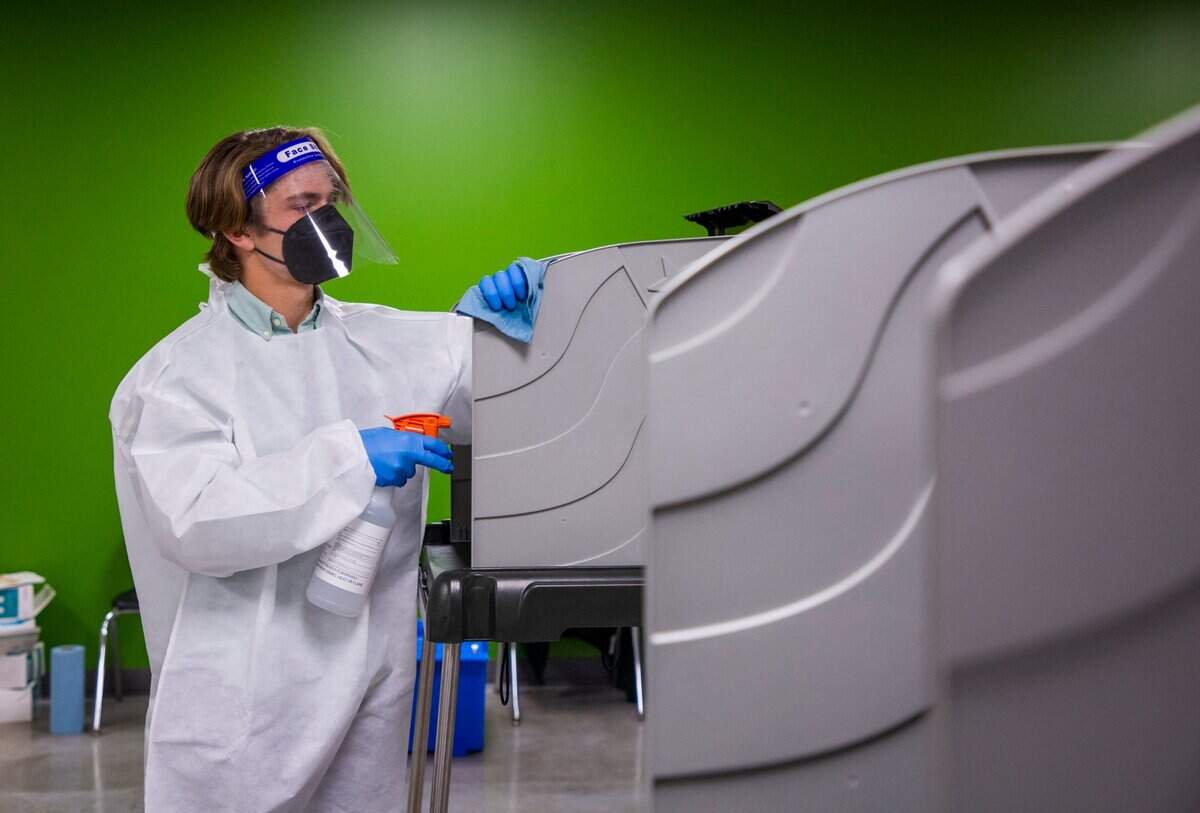 Jack Anderson cleans ballot boxes to prevent to spread of COVID-19 on Election Day at the Boys & Girls Clubs of Durham and Orange County, on Tuesday, Nov. 3, 2020, in Durham, N.C.