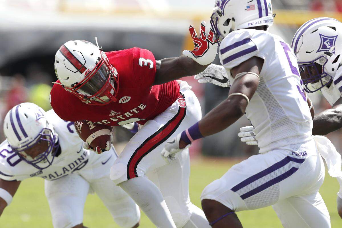 N.C. State’s Kelvin Harmon (3) looks to stiff-arm Furman linebacker Joe Farrar (5) at Carter-Finley Stadium Saturday, Sept. 16, 2017.