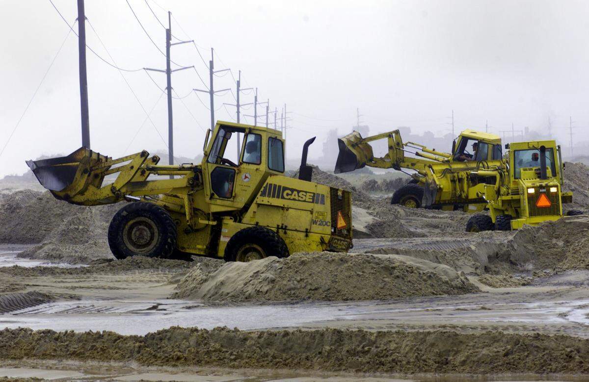 Heavy earth-moving equipment works on a section of Highway 12 north of Rodanthe that was overwashed and covered with several feet of sand after the dune line was breached by heavy surf from Hurricane Dennis. Several sections of the highway are covered with large amounts of sand and at least one section has severly damaged pavement. staff/scott sharpe