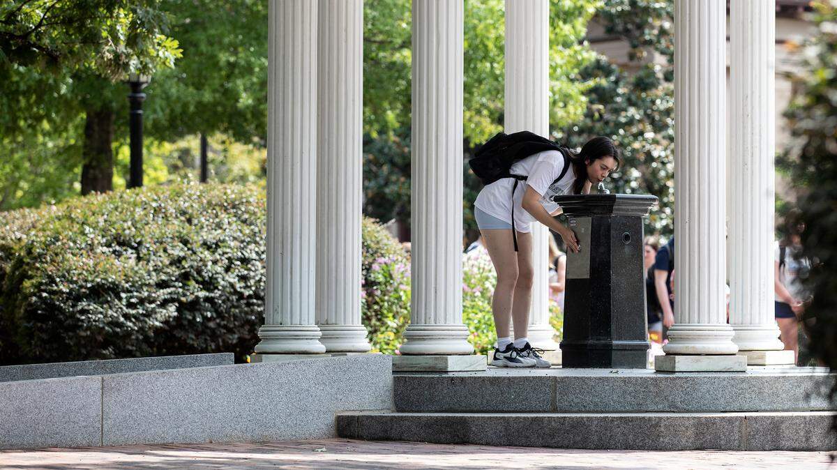 A person drinks from the Old Well on the first day of classes at UNC-Chapel Hill on Monday, Aug. 21, 2023.
