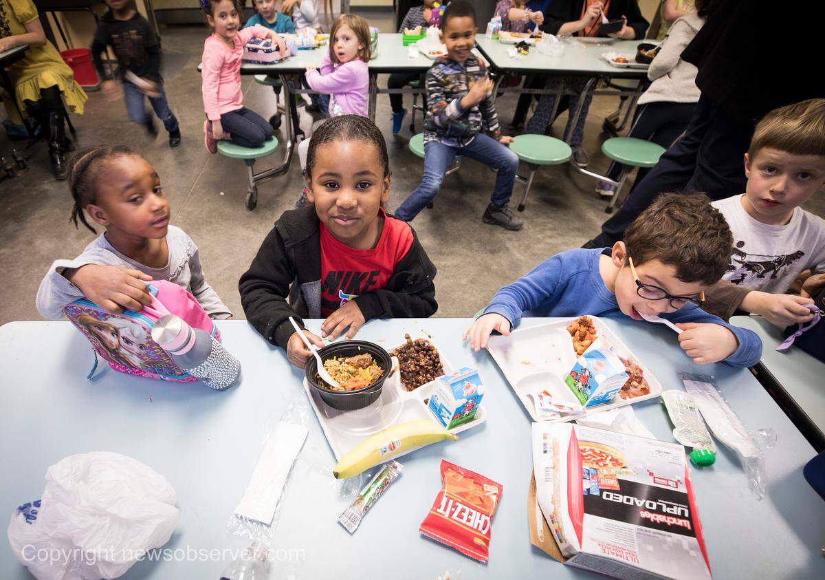 Demani Dargan-Juarez, 5, center, looks up in between bites of school lunch at George Watts Elementary School on Thursday, Jan. 24, 2019.